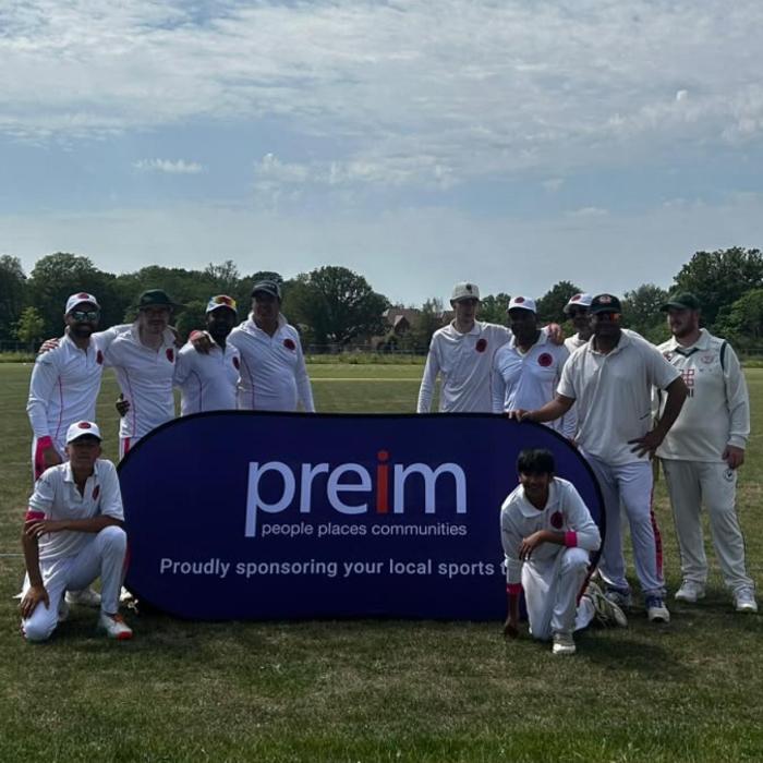 Cricket club players posing for a photo with a banner bearing the name of their sponsor
