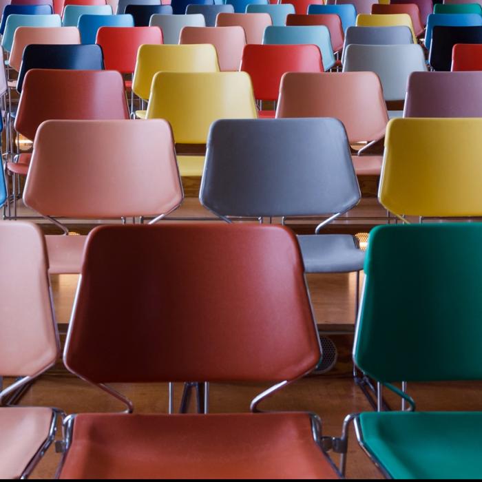 Colourful seats set up in rows like a theatre waiting for people to attend an event