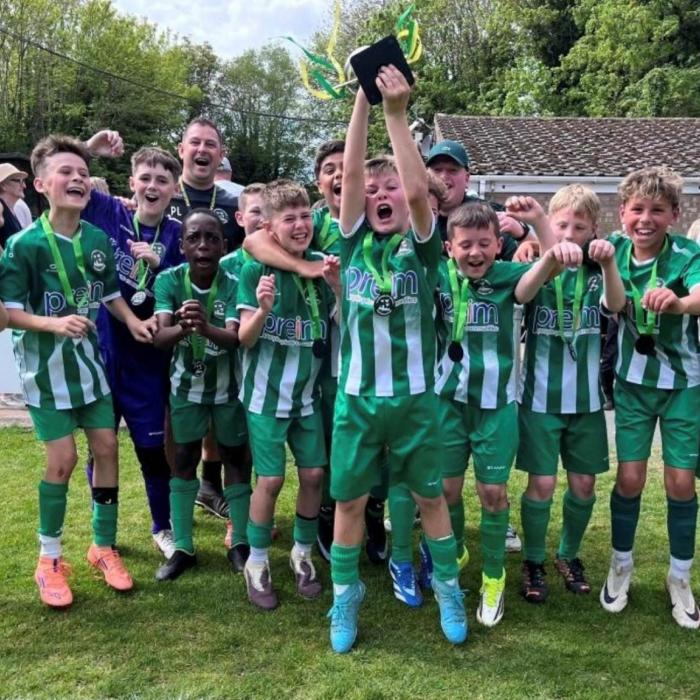A kids football tea celebrating their win on the green and white strip